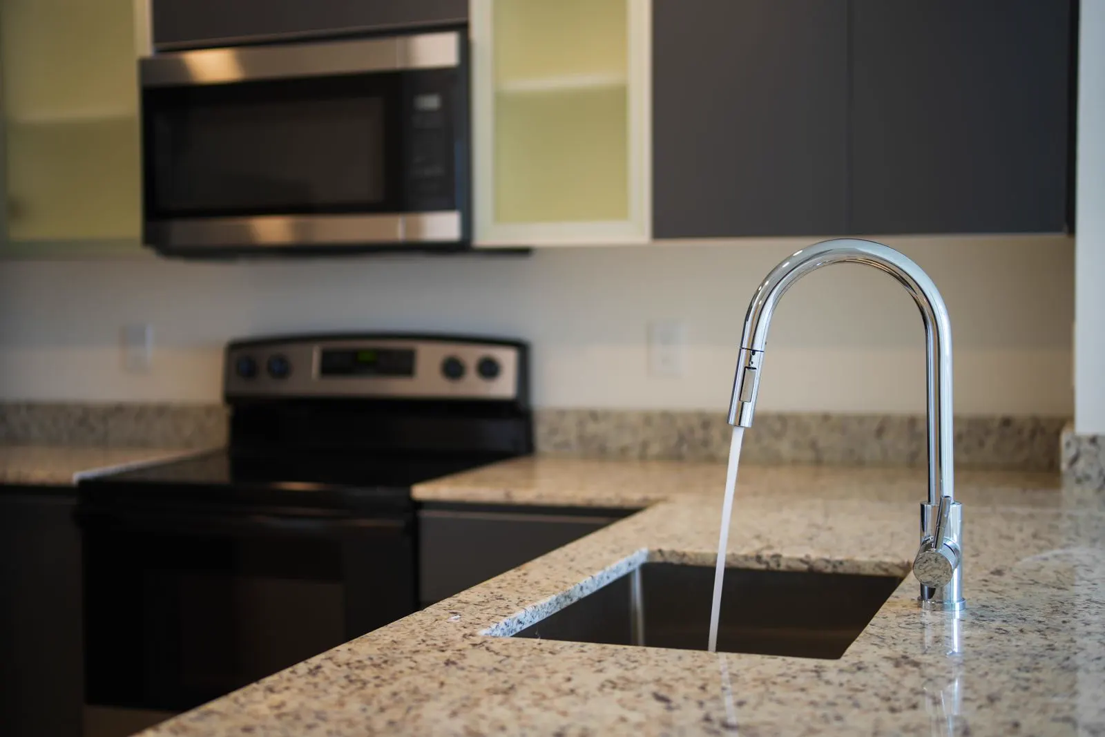 Kitchen faucet running into a sink on a granite countertop