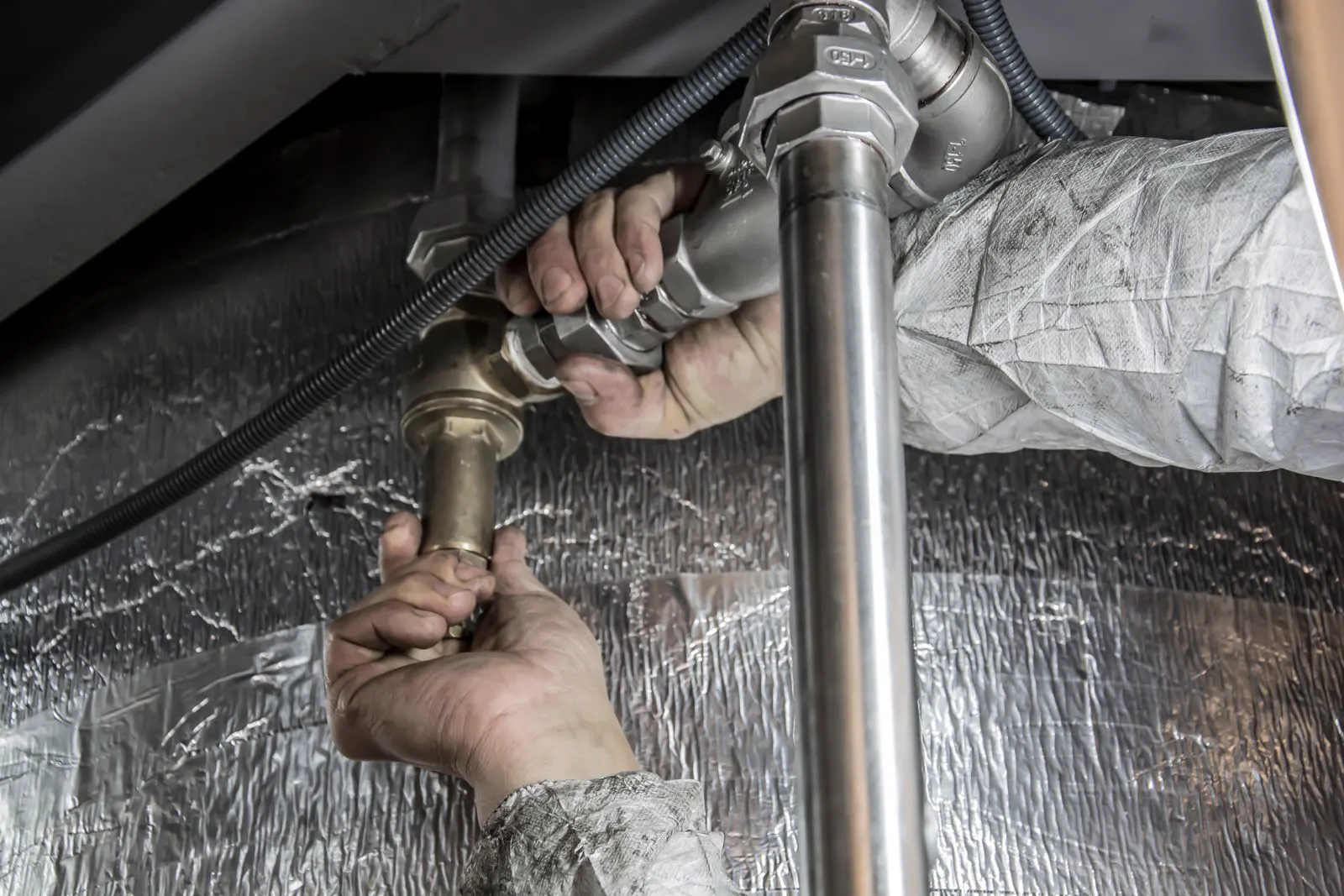 Plumber's hands tightening a metal pipe fitting
