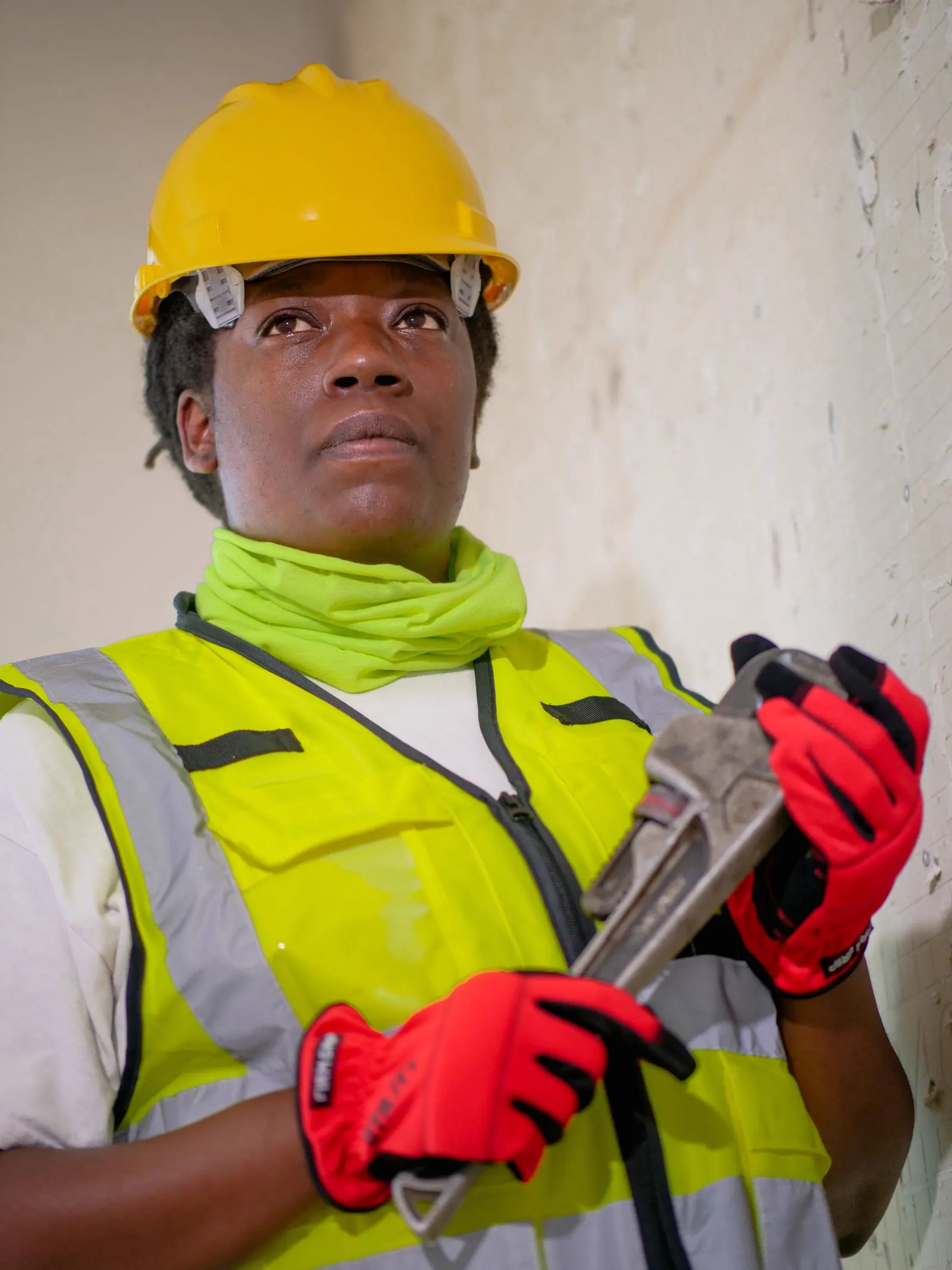 Plumber in a safety vest holding a pipe wrench