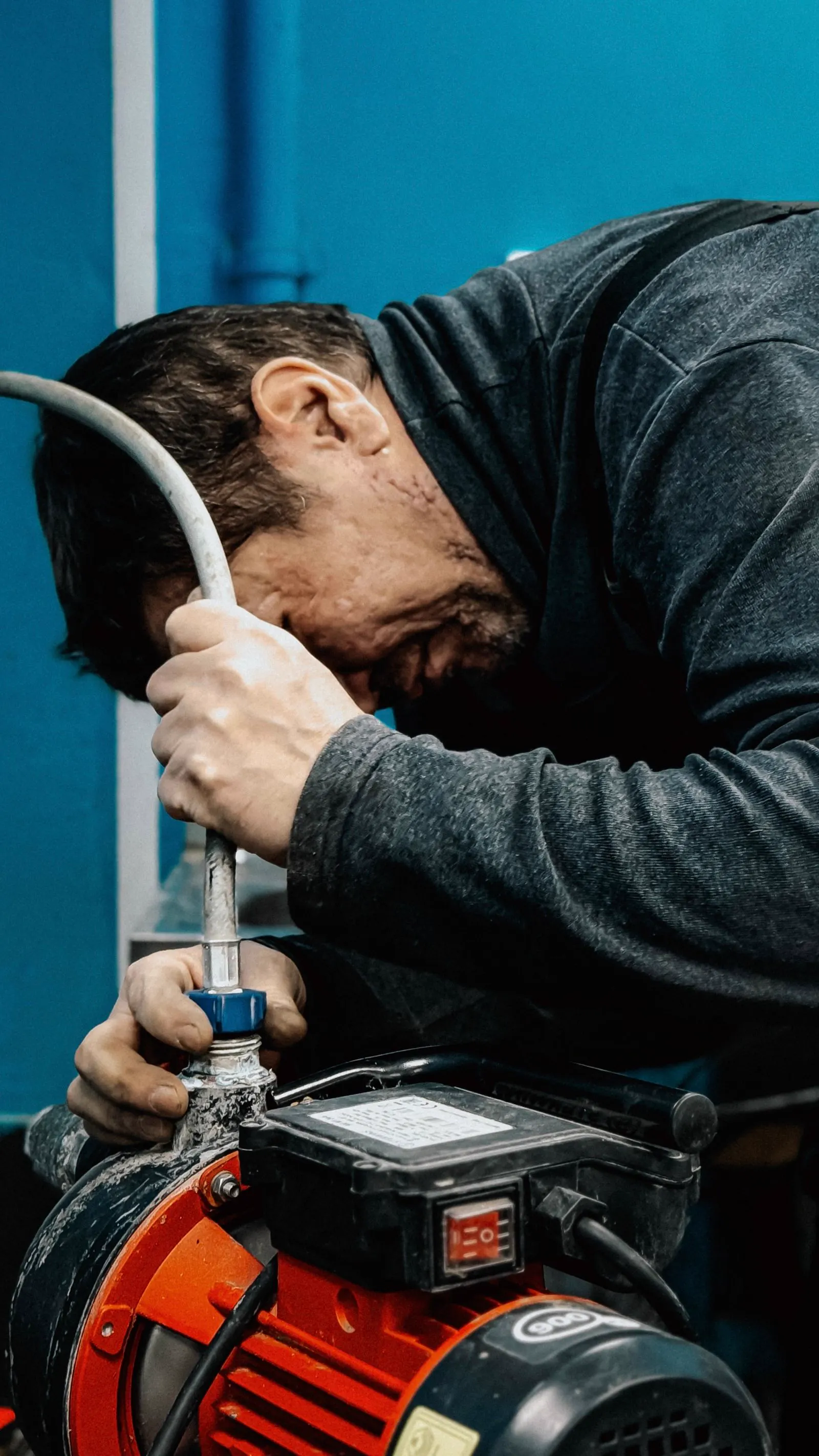 Plumber working on a water line with a supply hose